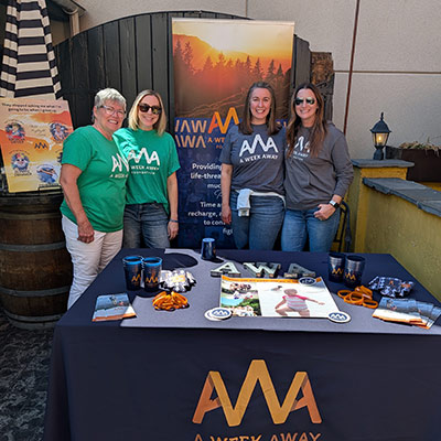 A Week Away staff and volunteers in front of an AWA expo booth.