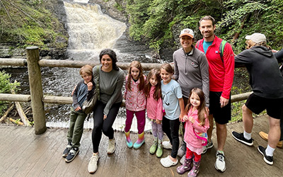 A family on respite in front of a waterfall, sponsored by A Week Away.