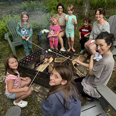 A family gathered around a fire making smores.