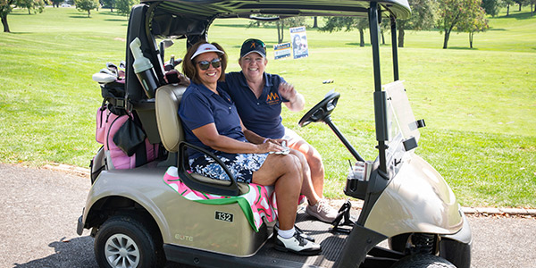 Two women in a golf cart at the Caleb Walker Memorial Golf Tournament.