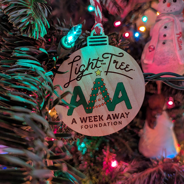 Close-up of a wooden "Light the Tree" ornament for the A Week Away Foundation.