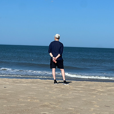 Man standing on the beach looking out into the ocean.